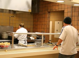 a photo of a teenager waiting for food at a cafeteria