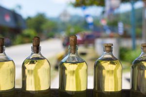 Selective focus on a row of glass bottles filled with transparent golden liquid like used oil cooking oil.